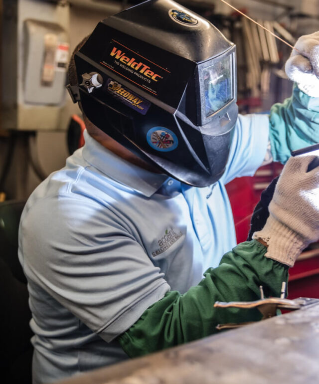 an adams campbell employee welding a metal component