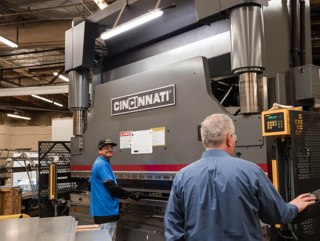 an adams campbell co. employee smiles while working the cincinnati machine